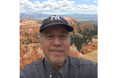 A person wearing a hat and smiling at the camera
Description automatically generated