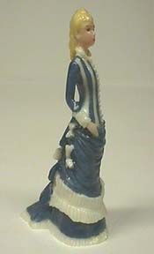 Lady of 1876 in draped slate blue gown with white ruffles.